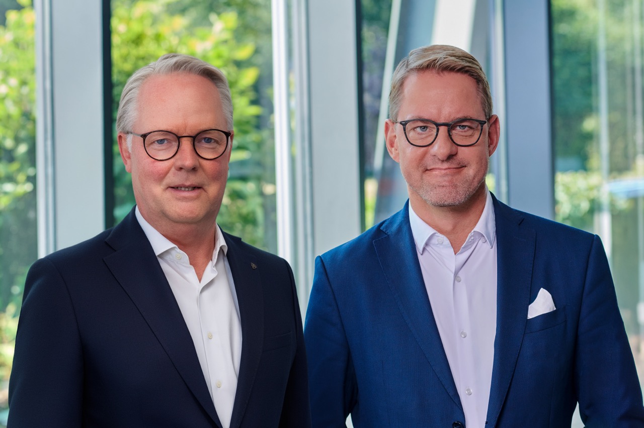 Od lewej: Jürgen Deters i Tobias Schulz (zarząd) w jasnym foyer z dużymi oknami i roślinami w tle.