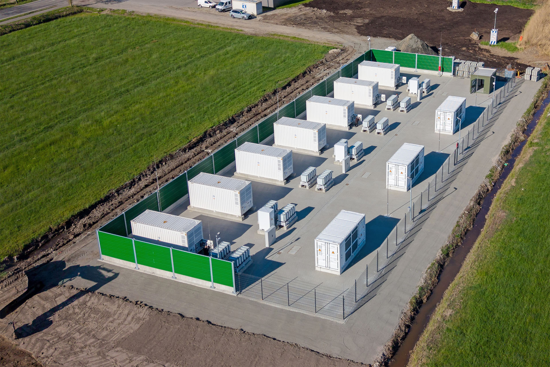 Widok z lotu ptaka na magazyn energii z kontenerami i ogrodzeniem.