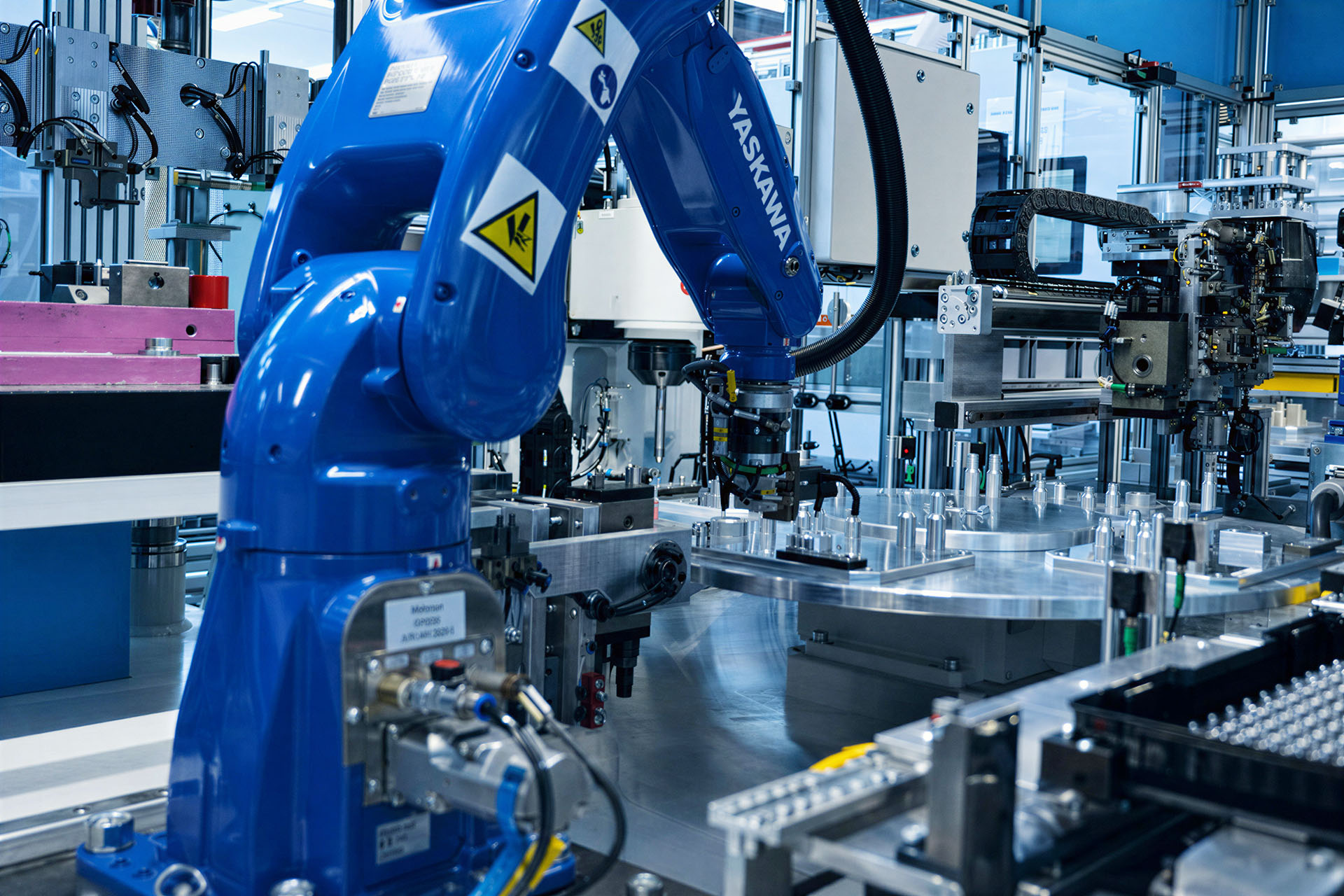 Robot 6-osiowy umieszcza wkładki w obrotowej celi wtryskowej.