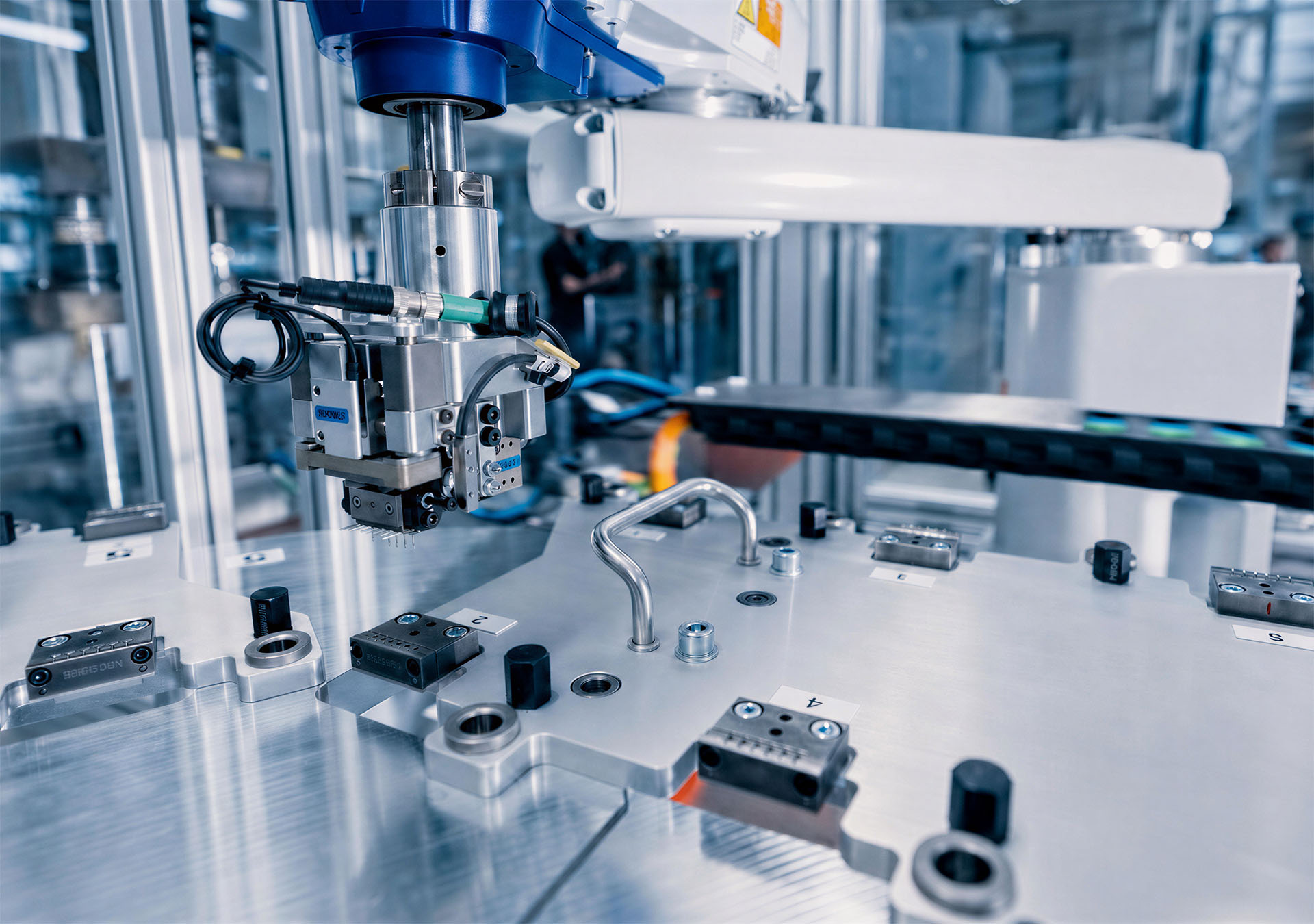 System chwytaka robota nad przyrządem w zautomatyzowanej celi produkcyjnej.